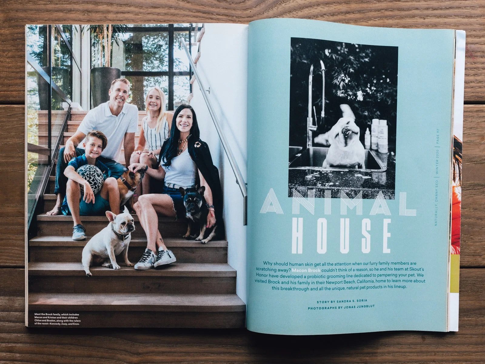 Open magazine spread featuring a color photo of a family with dogs seated on wooden stairs indoors and a black-and-white photo of a dog in a sink on the opposite page, with text discussing pet grooming and family stories.