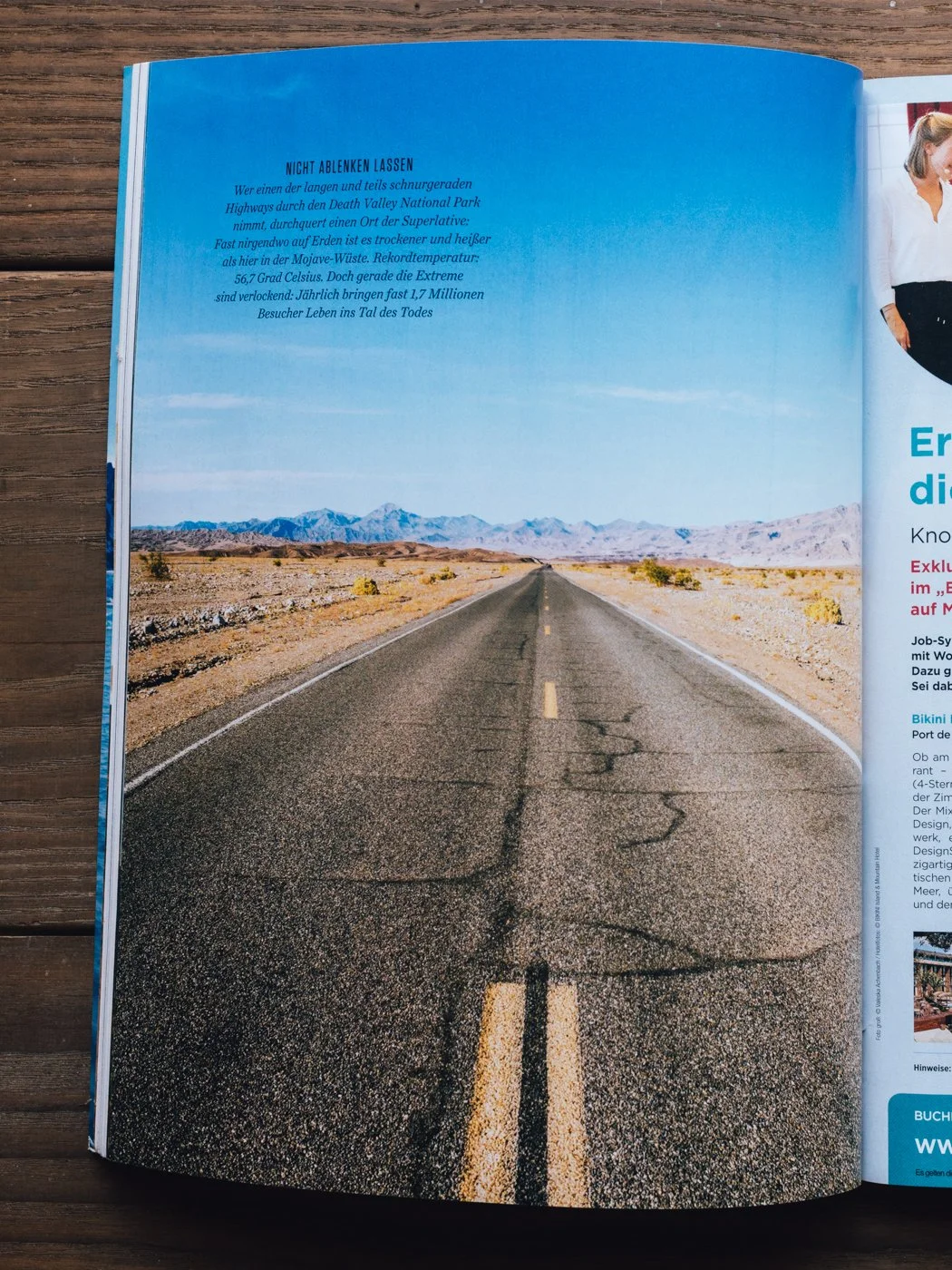 Open magazine showing a long deserted road through a desert landscape with distant mountains under a clear blue sky.