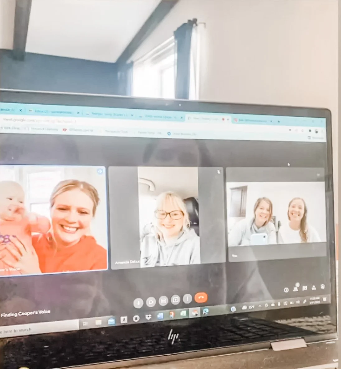 Laptop screen displaying a video call with three frames featuring smiling people.