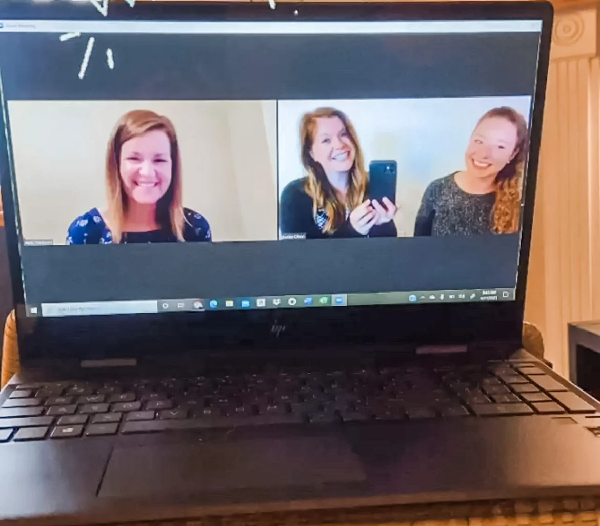 Laptop screen showing a video conference with three people smiling