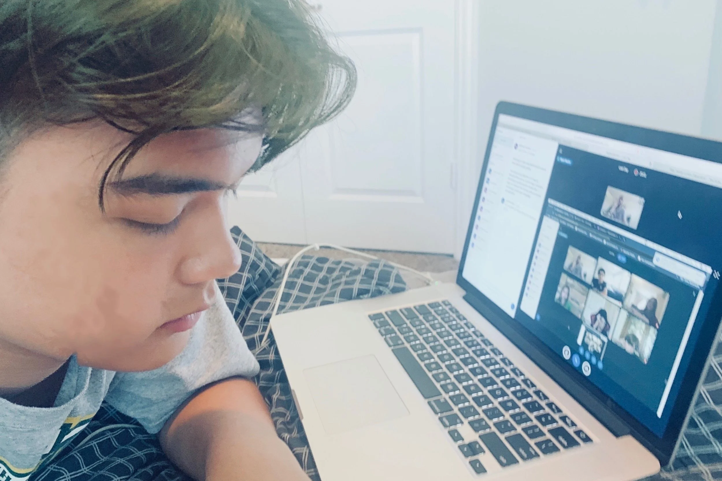 Person using a laptop for a video call with multiple participants visible on screen.