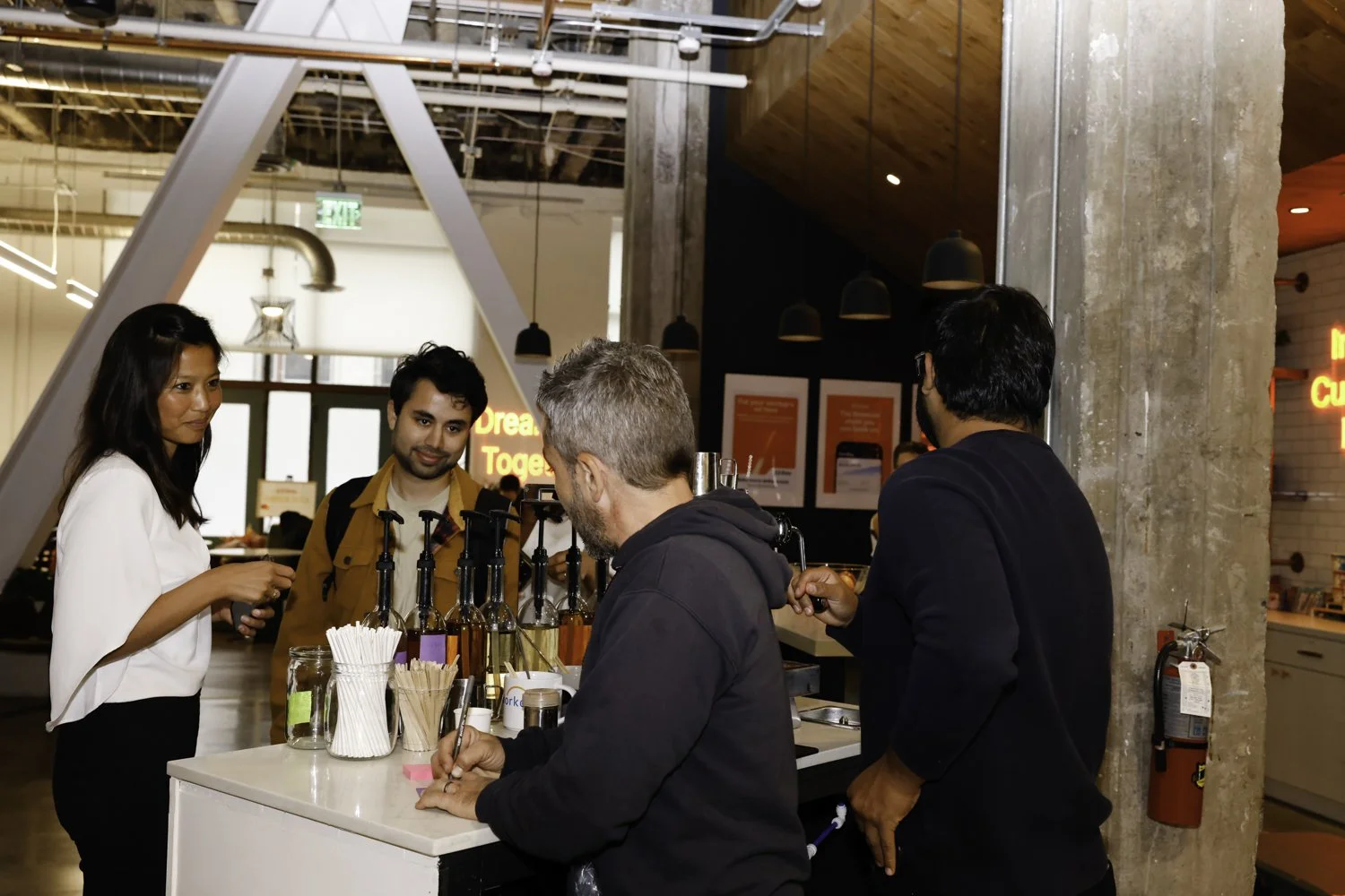 People ordering drinks at a counter in a modern, industrial-style cafe or bar Brex headquarter in San Francisco, CA.