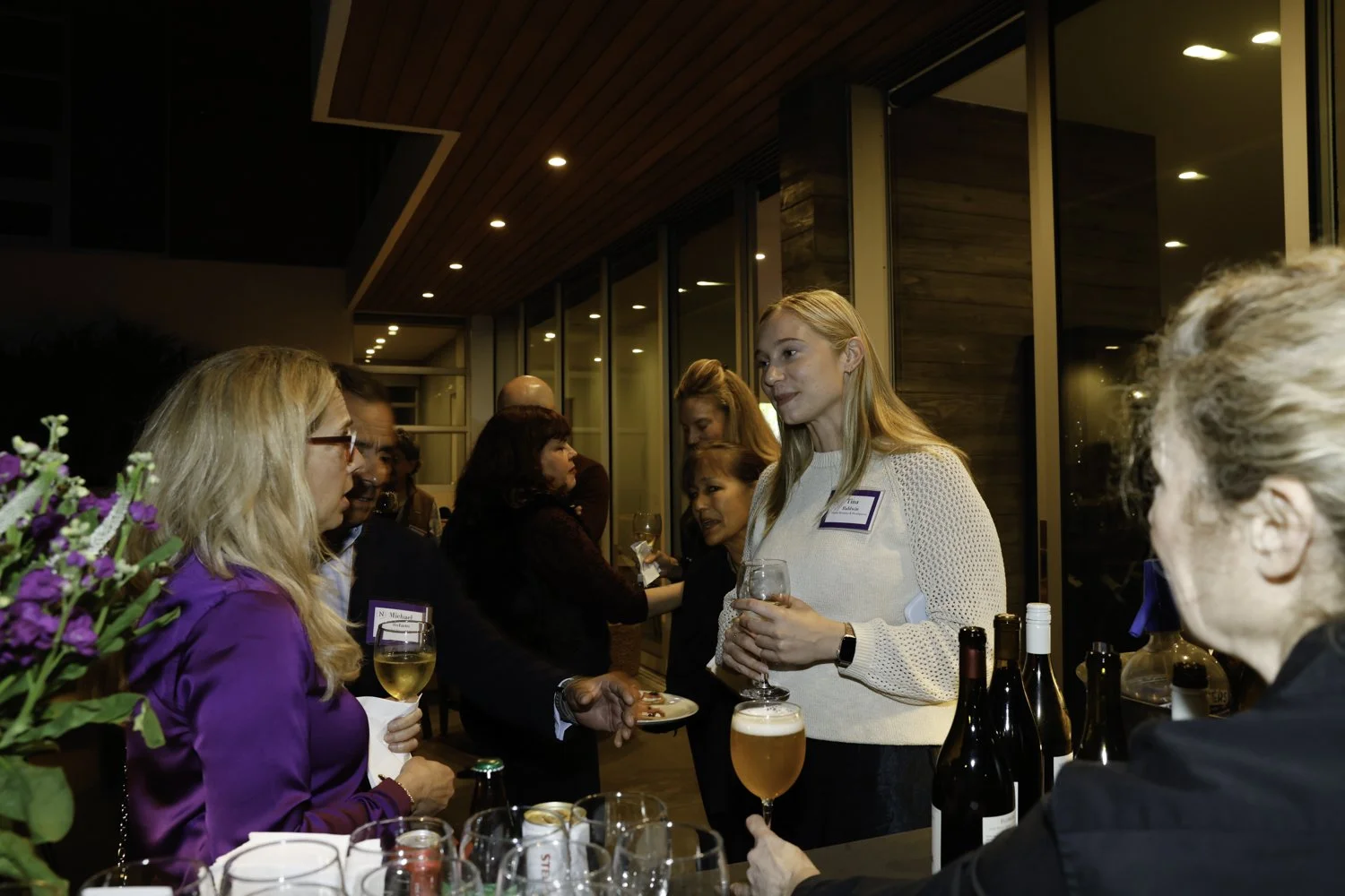 People socializing at a bar or reception, holding drinks and engaging in conversation Brex headquarter in San Francisco, CA.