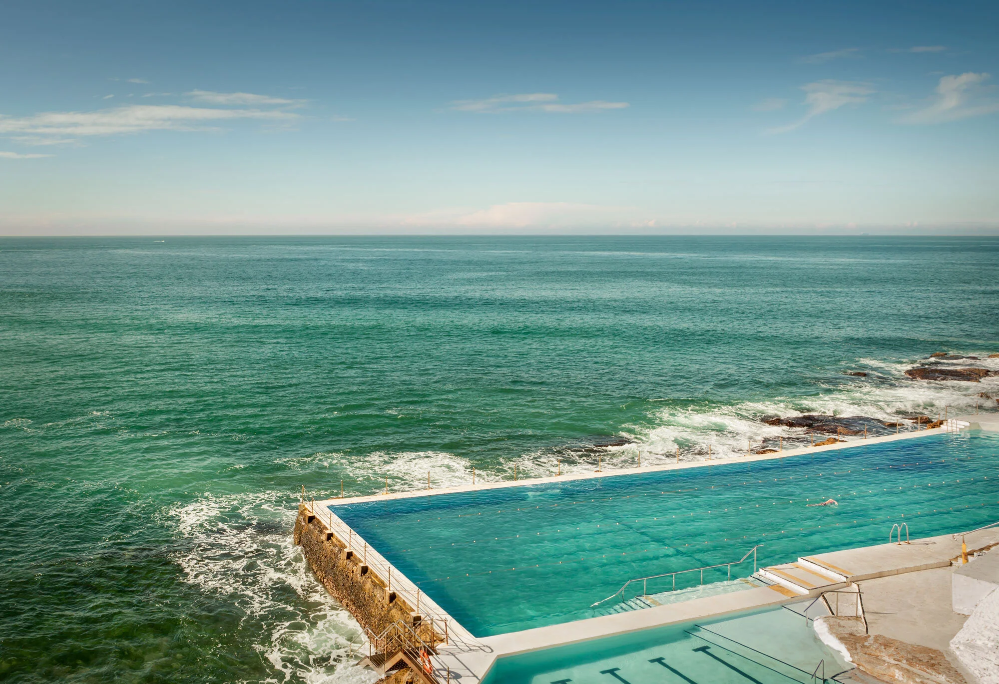 A rooftop infinity pool overlooking the ocean with a clear blue sky above at Bondi Beach in Australia.