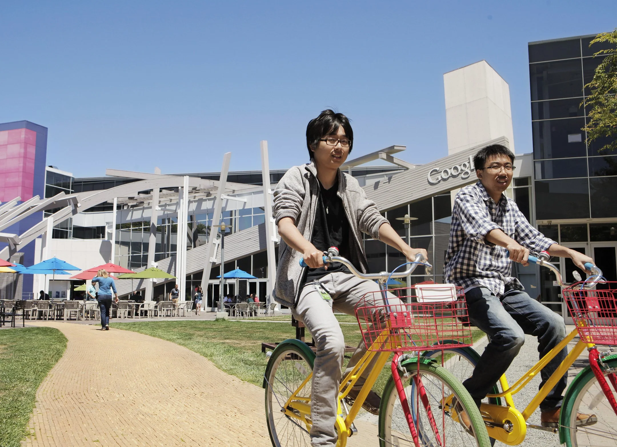 Two young men biking on Google bikes tutside Google headquarter at Mountain View in CA.