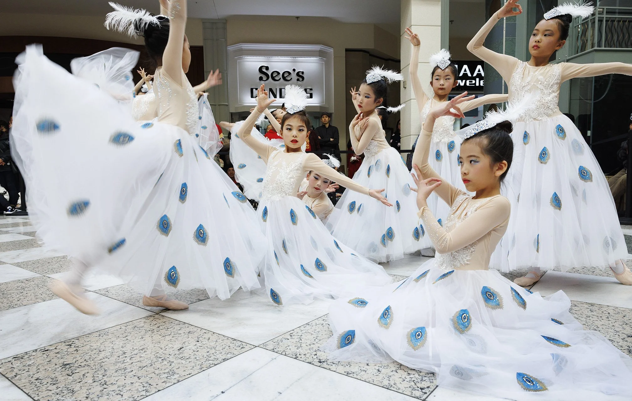 Group of young Asian girls in peacock costumes performing a dance in a shopping mall for the Lunar Year celebrations in San Francisco, CA.