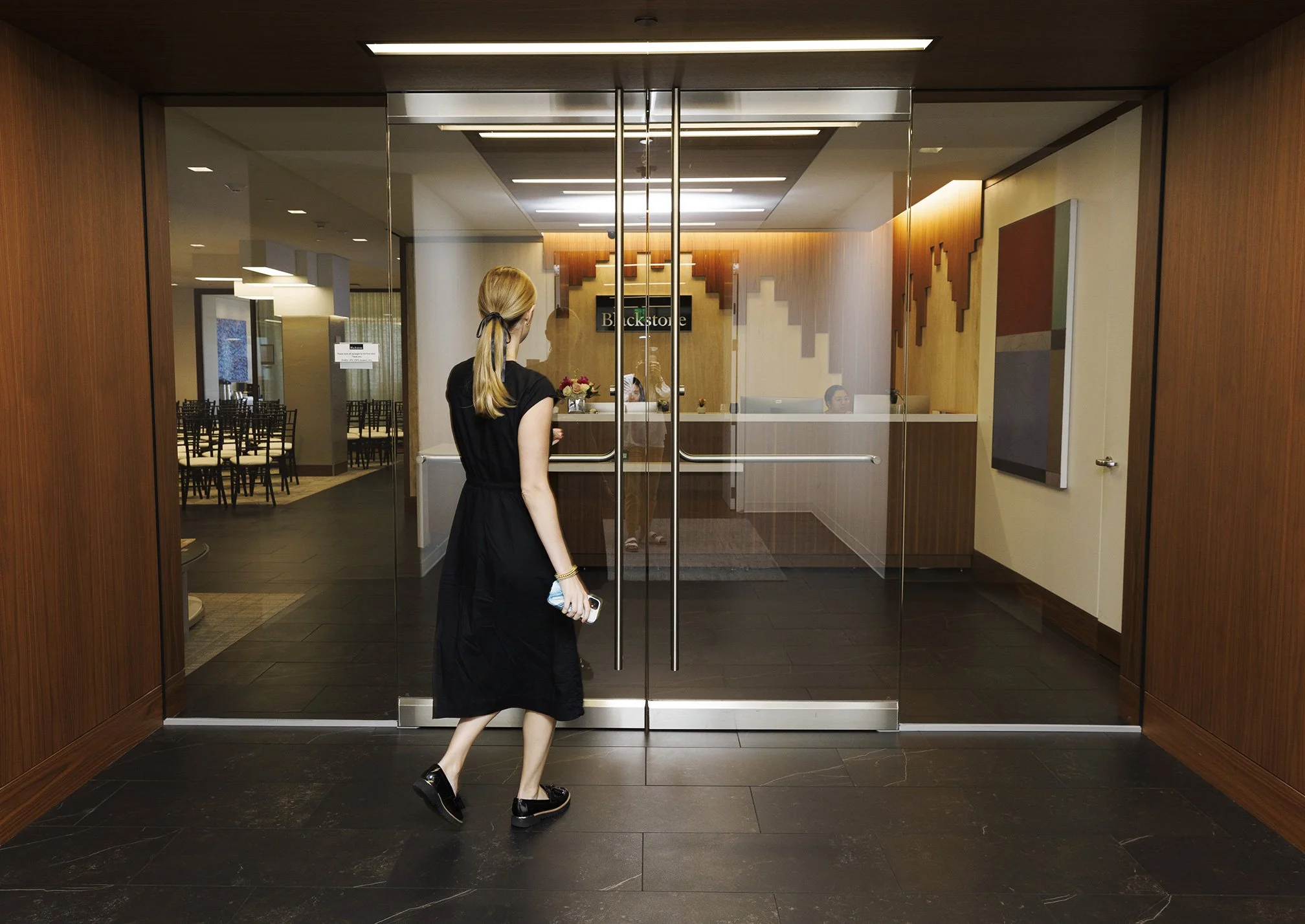 Woman dressed in a black dress walking through the door at Blackstone office in San Francisco, CA.