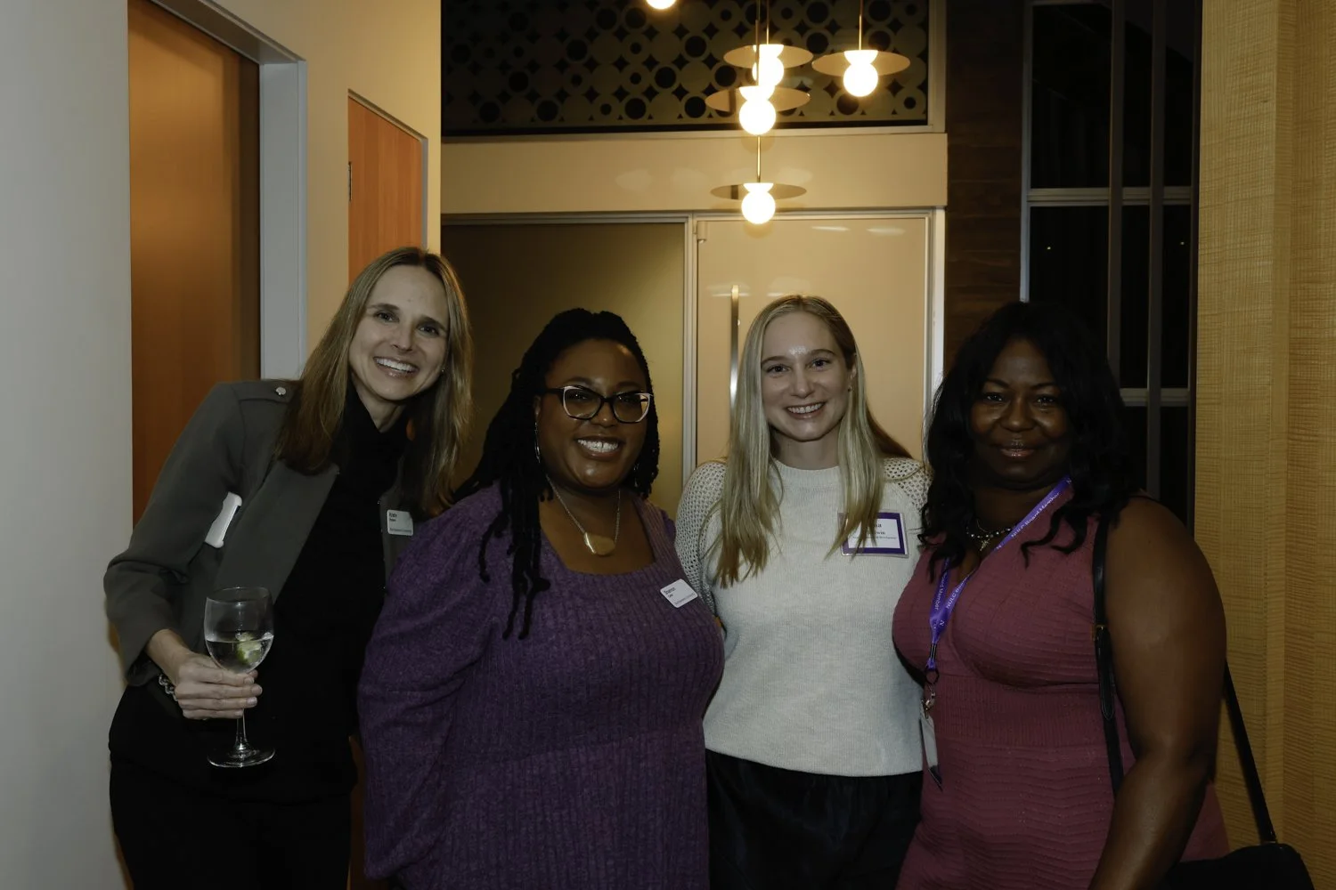 Four women at an indoor event, smiling and posing for a photo, with two holding drinks at Northwestern fundraiser in San Francisco, CA.