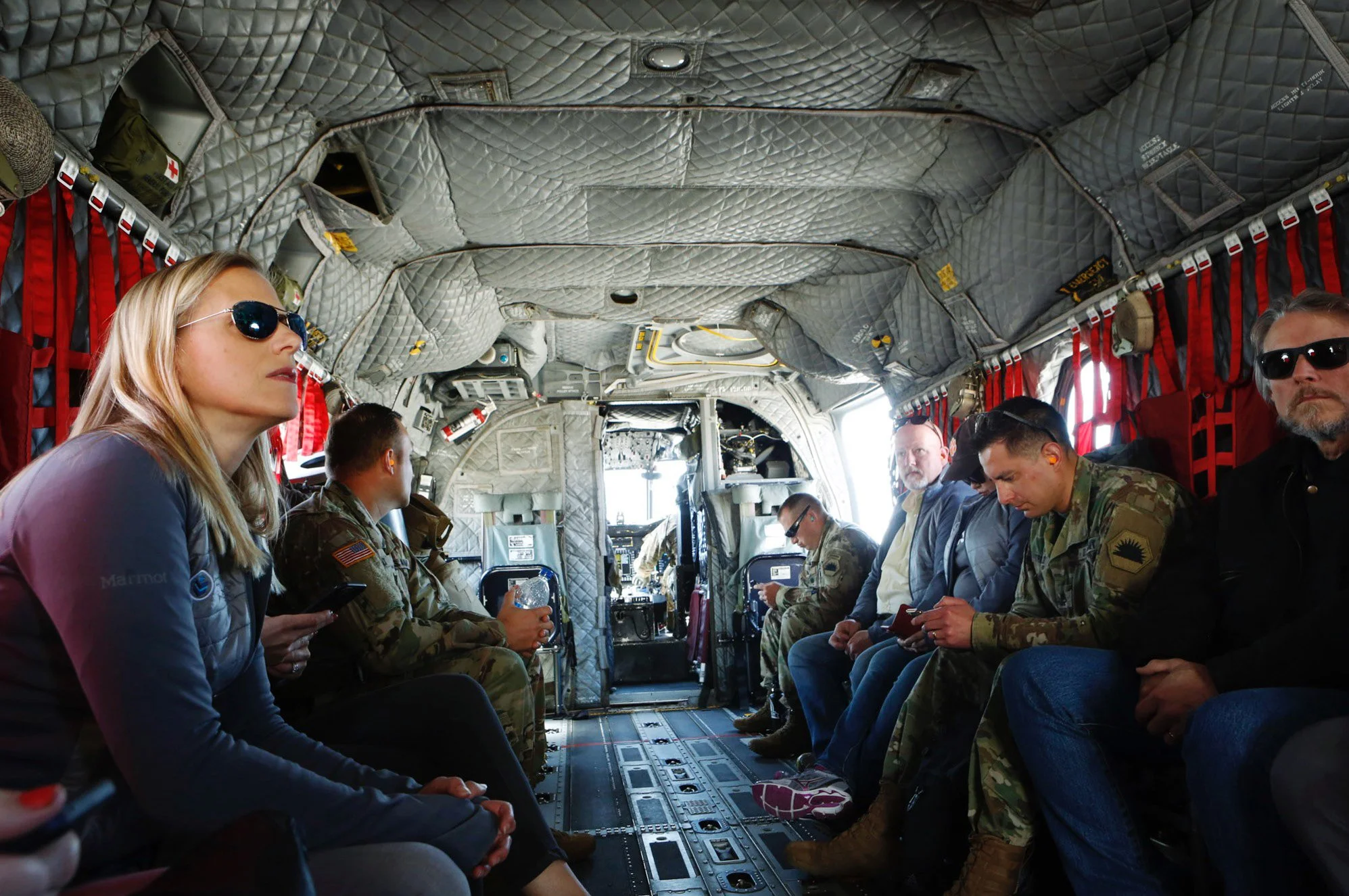 People sitting inside a military aircraft (helicopter) in the air flying over San Francisco, CA. Photographed Salesforce Trailhead Military (Military Veteran Recruitment Strategy) on location in California.
