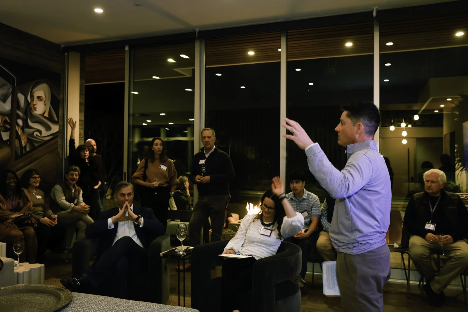 Man giving a presentation to a group of people in a modern lounge or conference room with large windows and artwork on the wall at Northwestern fundraiser in San Francisco, CA.