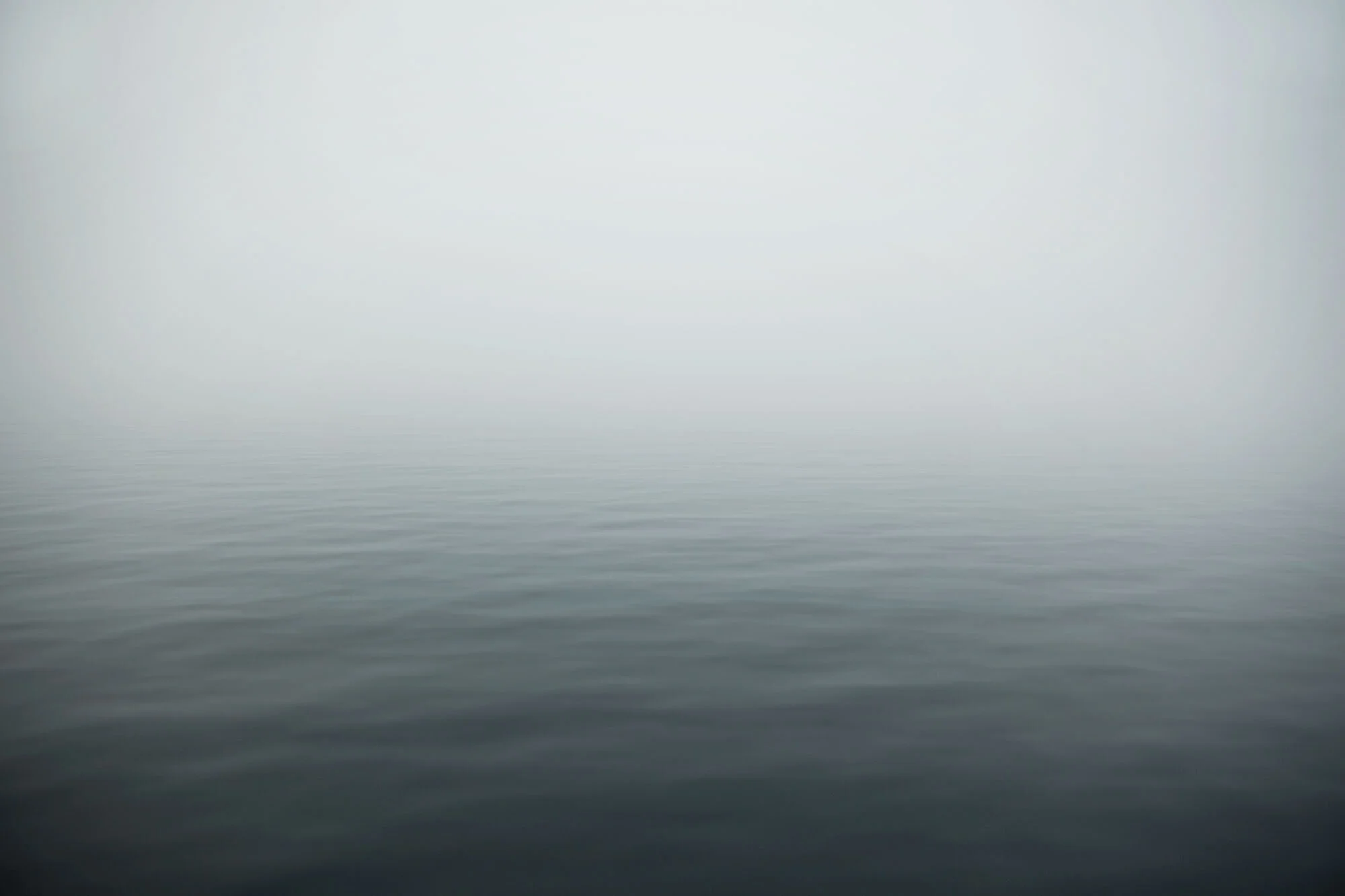 Water covered with dense fog blurring the lines of surface and sky at the end of the day in Lofoten, Norway.