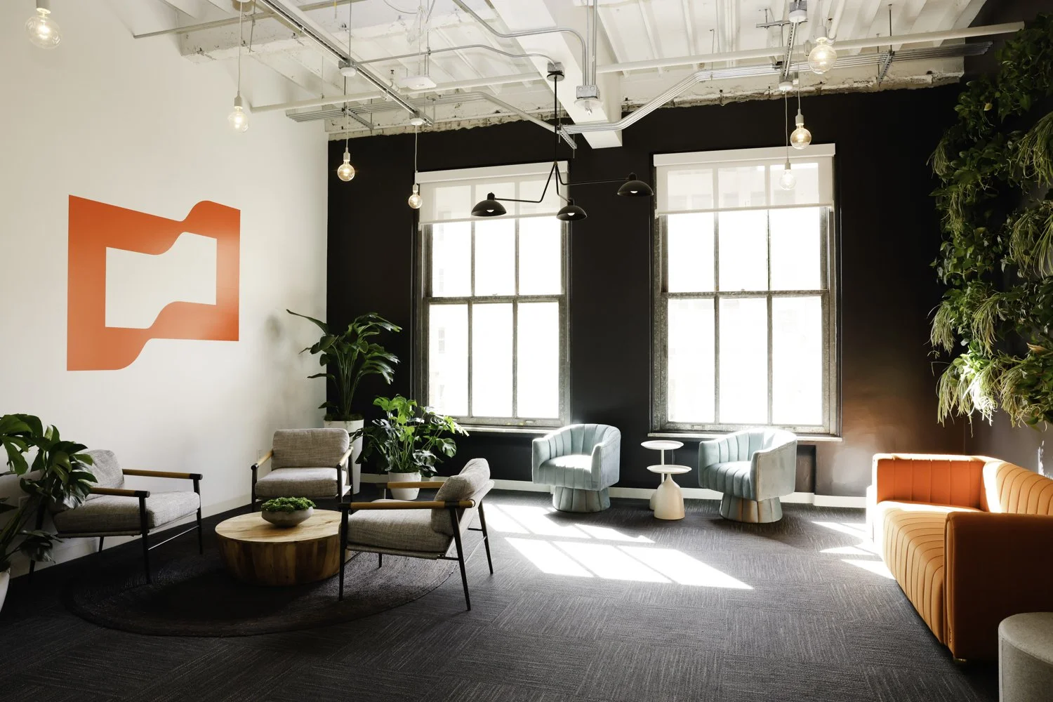 Modern office lounge with natural light, featuring lounge chairs, a sofa, plants, and contemporary decor at Brex Headquarter in San Francisco, CA.