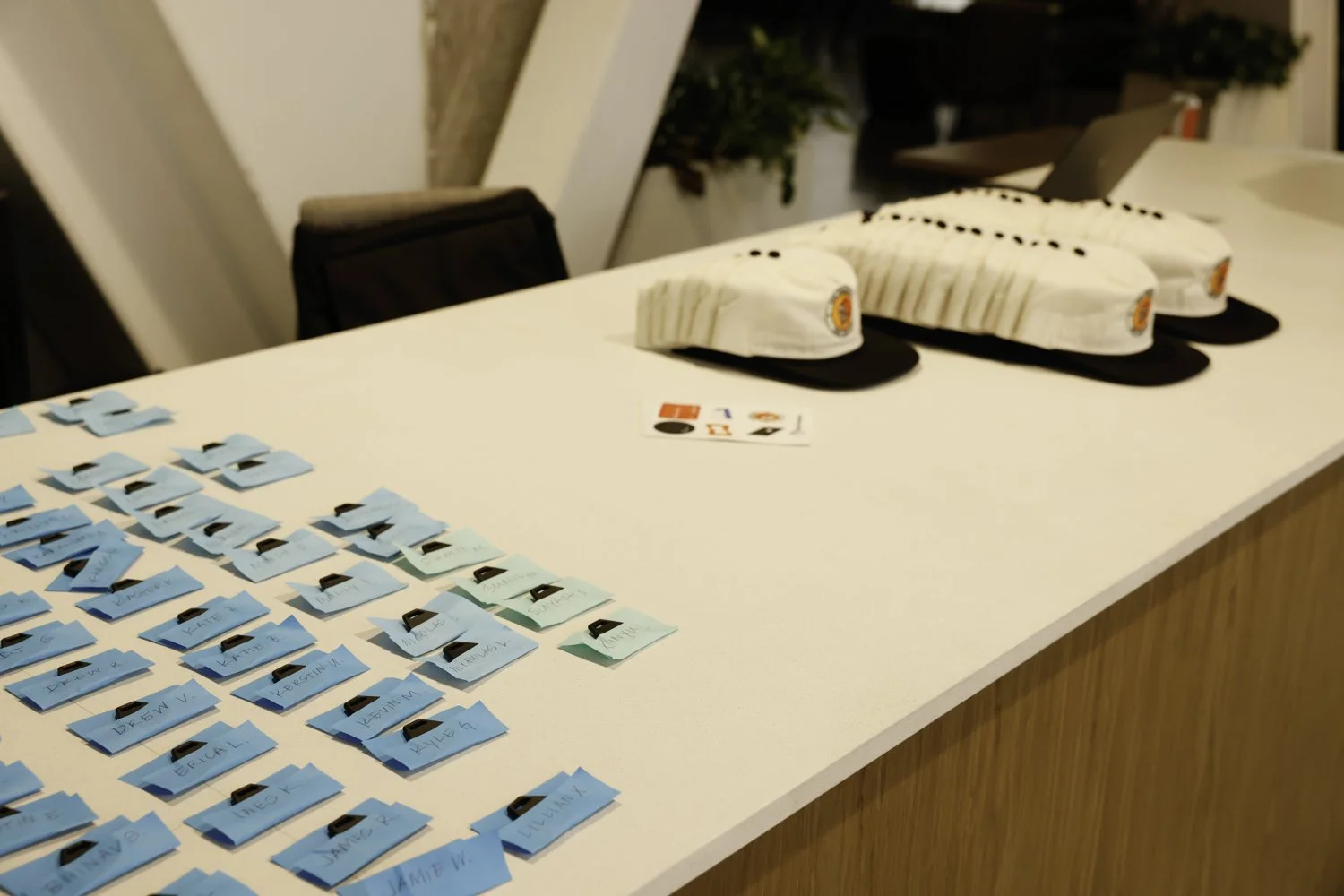 White table with multiple robot chef hats and name tags, along with business cards for a robotics or team event Brex headquarter in San Francisco, CA.
