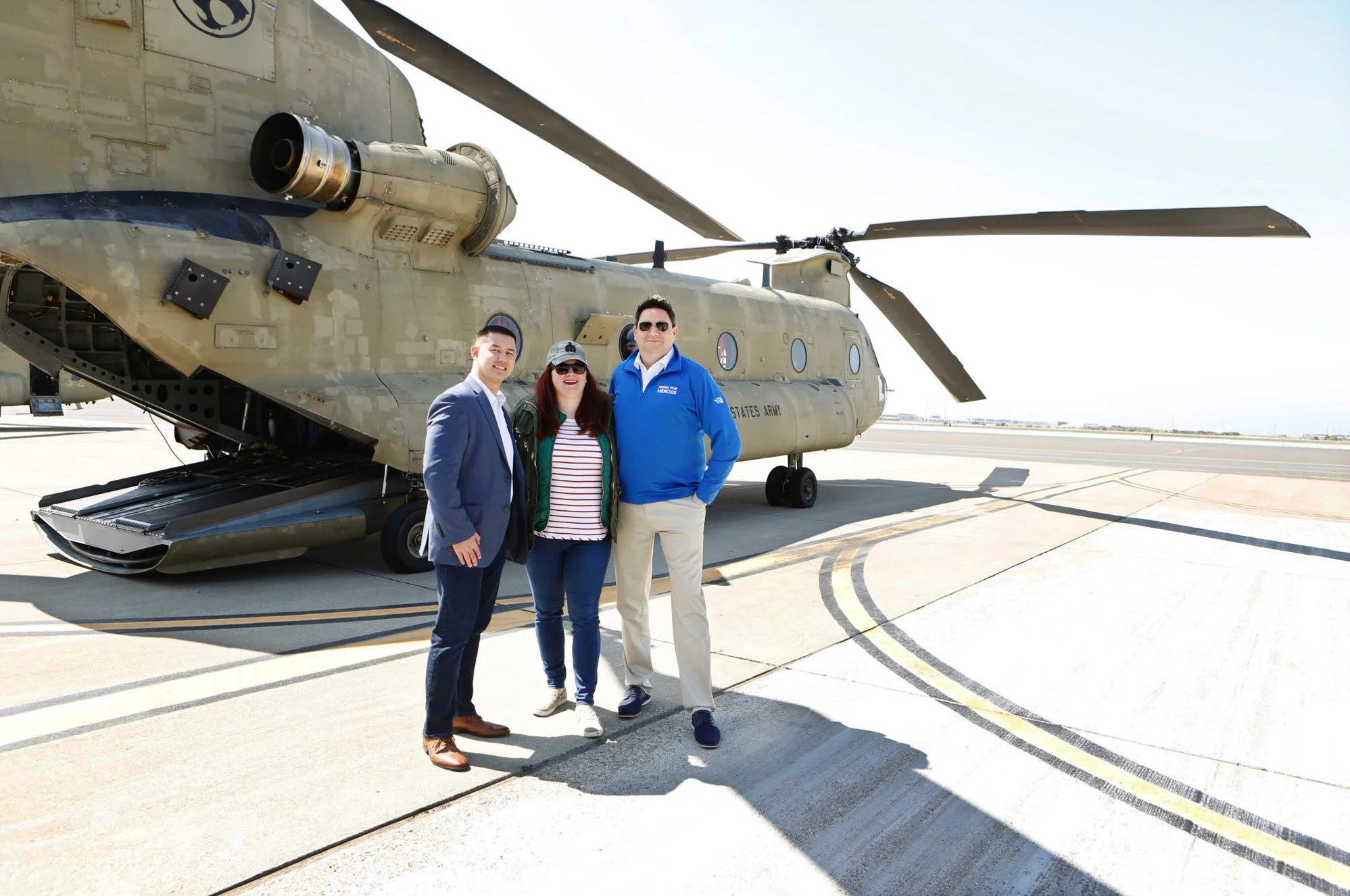 3 people standing in front of a military helicopter/aircraft on an airfield during a clear day. Photographed  Salesforce Trailhead Military (Military Veteran Recruitment Strategy) on location in California.