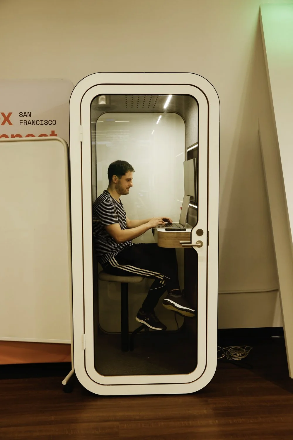 A man working on a laptop inside a Glass-door Focus Booth at a tech company at Brex headquarter in San Francisco, CA.
