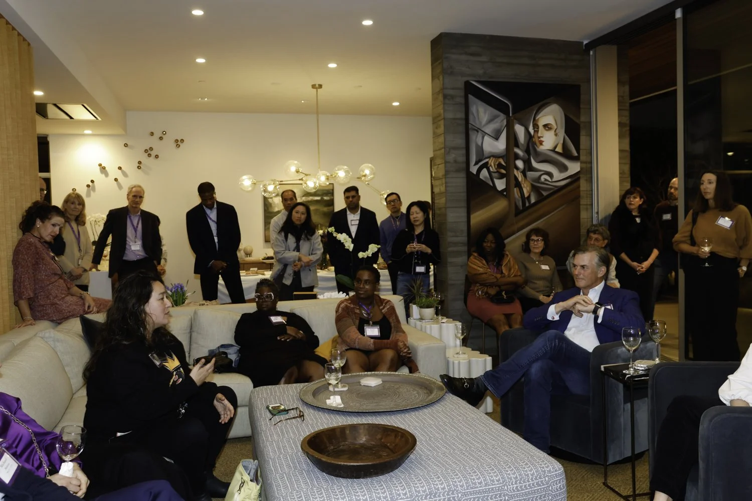 People gathered in a modern living room, some sitting on couches and others standing, attending a social event or gathering at Northwestern fundraiser in San Francisco, CA.