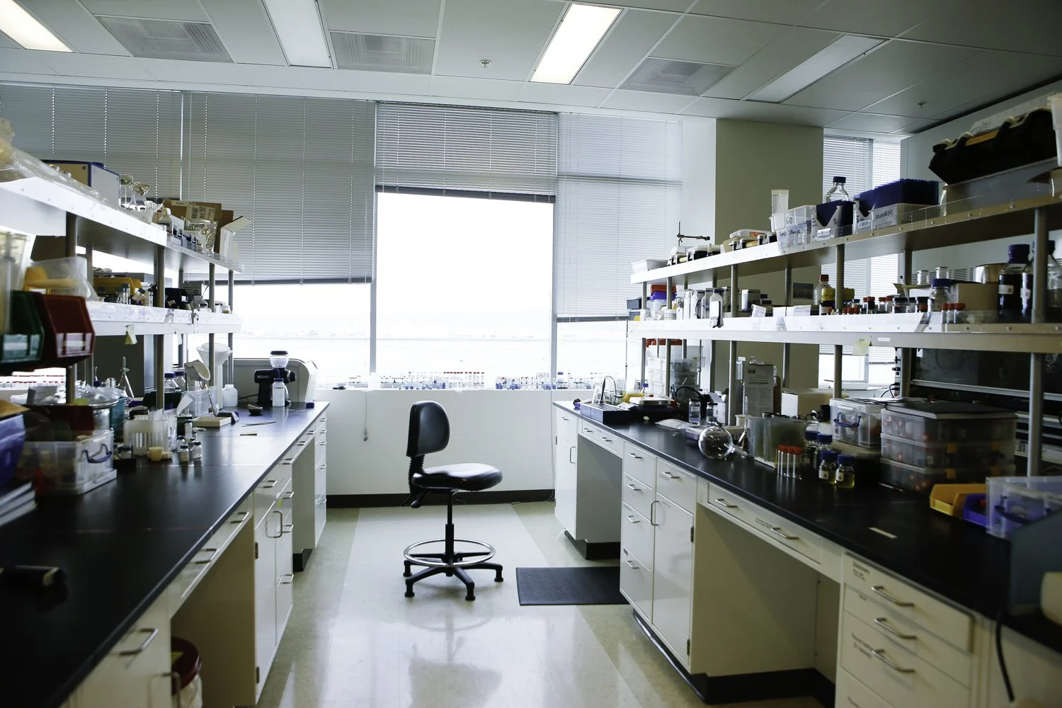 Science lab with tools, vials, equipment, drawers and shelves against a window and a chair in San Francisco, CA.