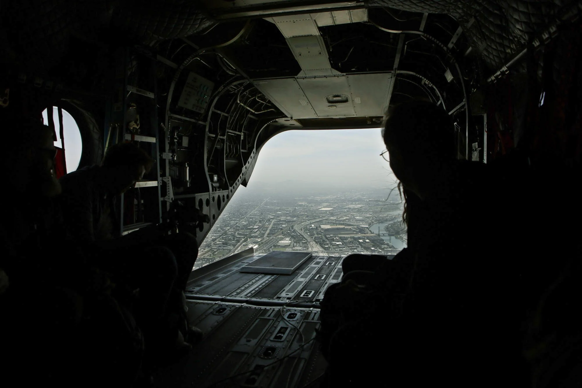 Inside a darkly lit military helicopter with the backdoor open where you see San Francisco in the distance photographed for Salesforce Trailhead Military (Military Veteran Recruitment Strategy) on location in California.