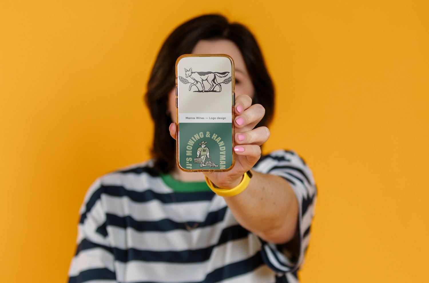 Photo of Amy against a yellow backdrop holding a phone up to the viewer
