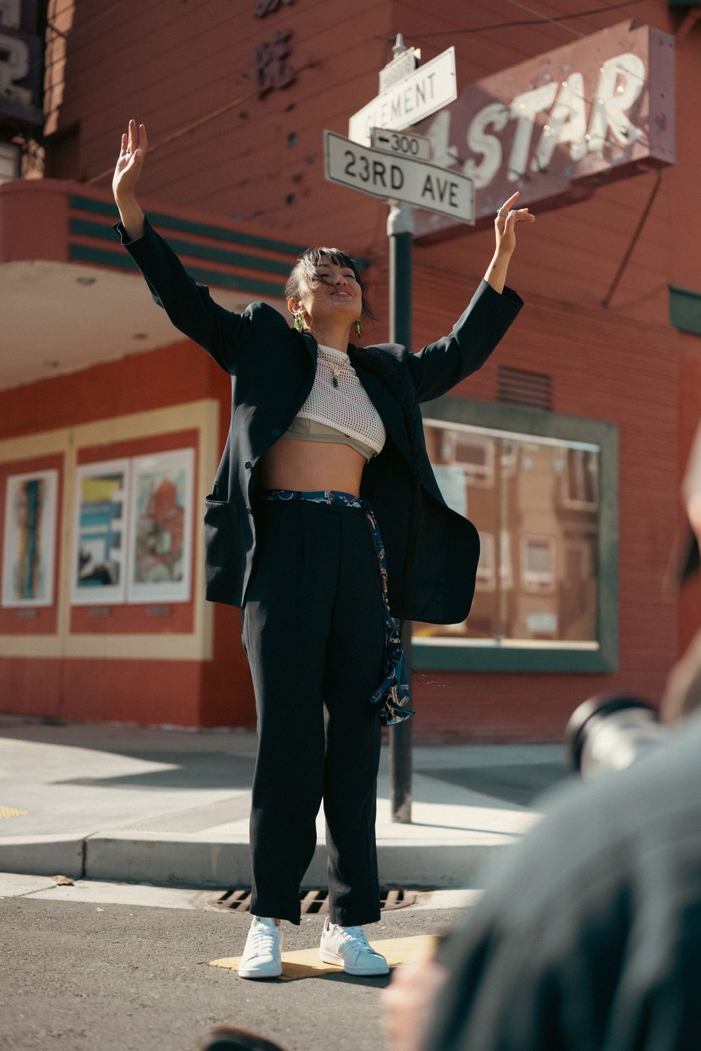 Woman with arms raised under a street sign