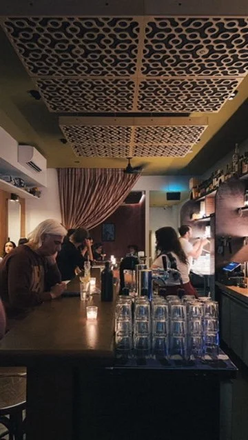 Image of a bar, showing patrons having drinks along its length