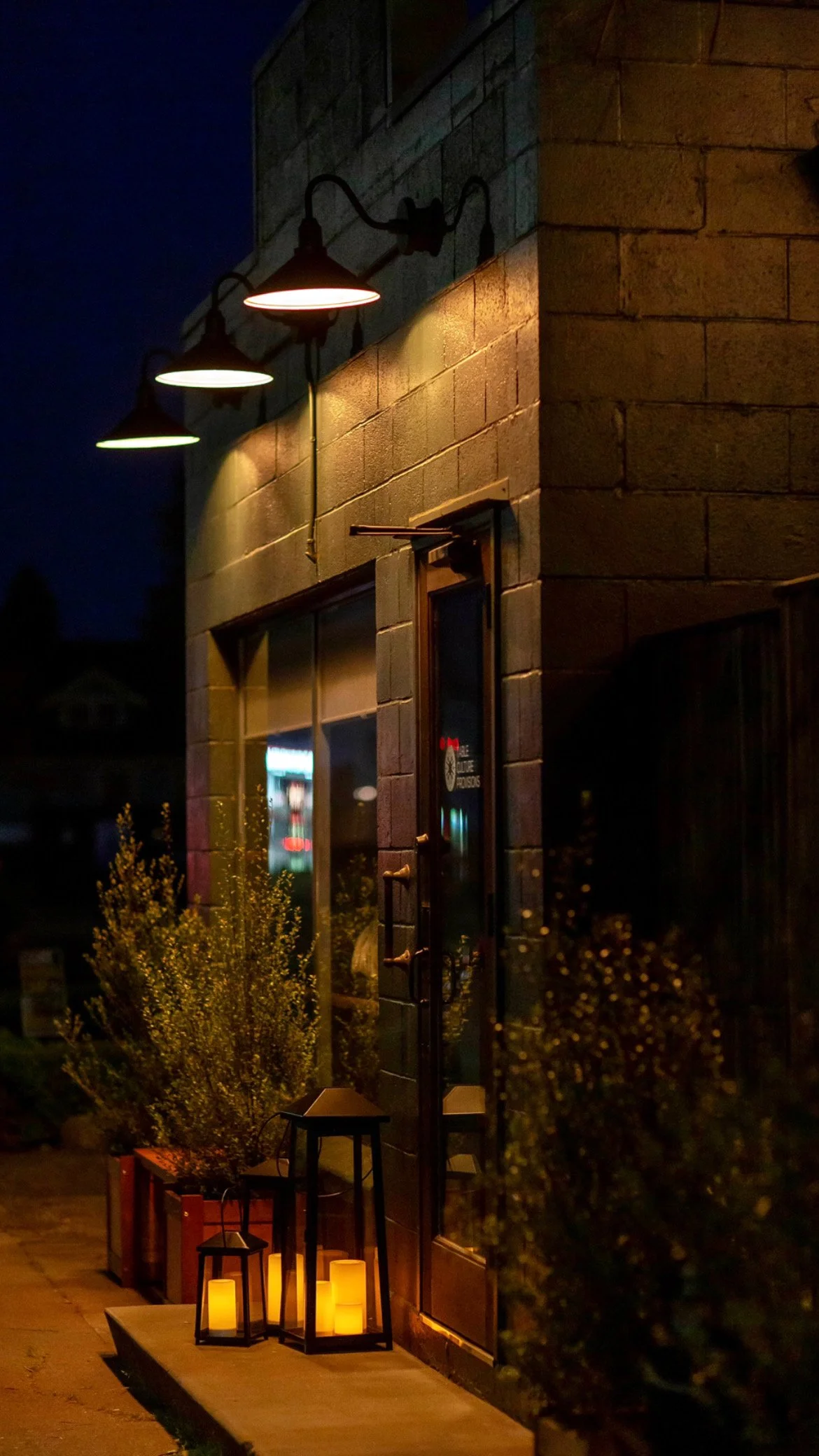 The Table Culture Provisions entrance at night, with lanterns by the door