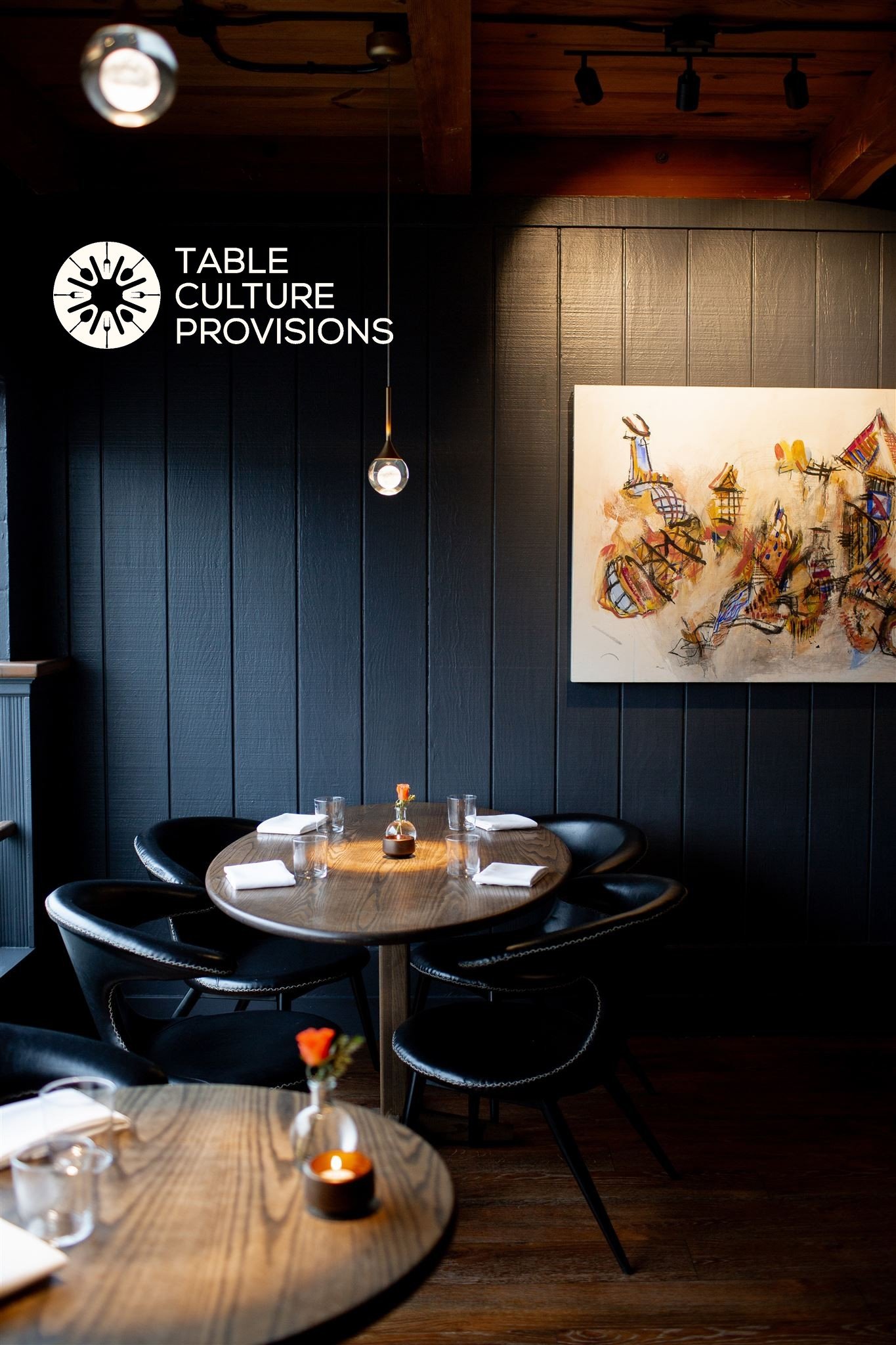 The dining room at Table Culture Provisions, with a set table and the logo on the wall