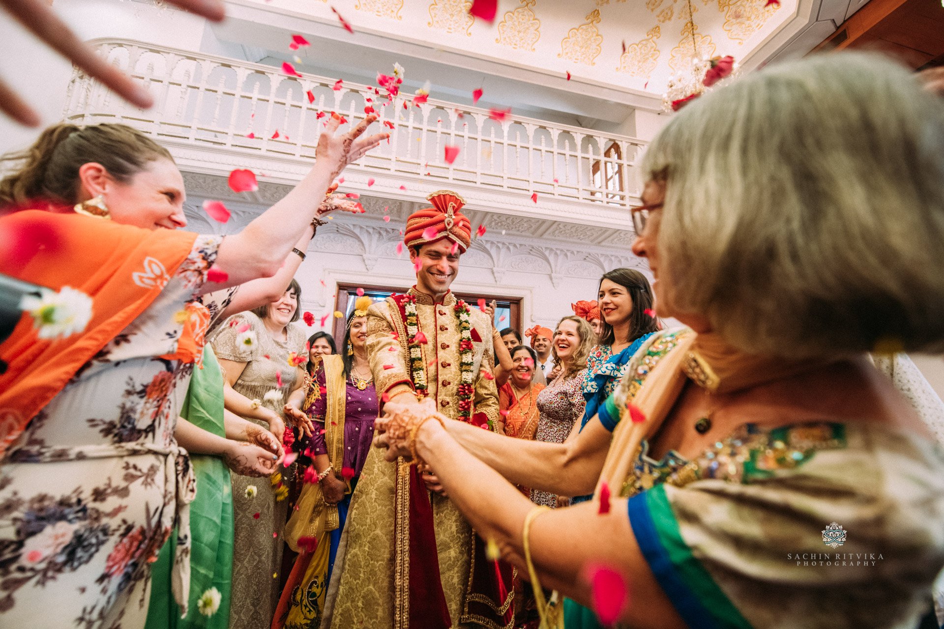 Indian wedding celebration og a european bride and family with an Indian groom in traditional attire, surrounded by European / Polish guests throwing flower petals.