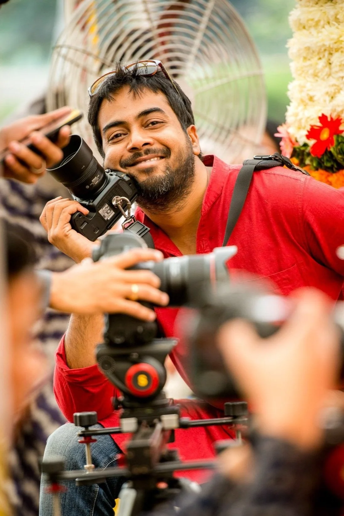 Photographer Sachin from SachinRitvika Photography holding camera in red shirt smiling