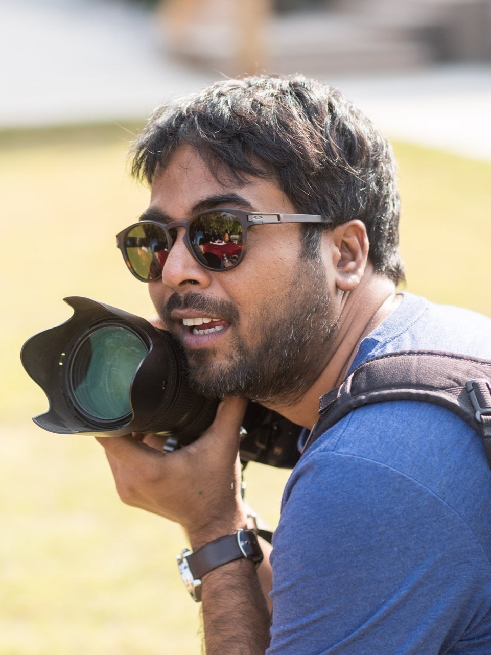 Sachin from SAchinRitvika in sunglasses holding a camera in a park