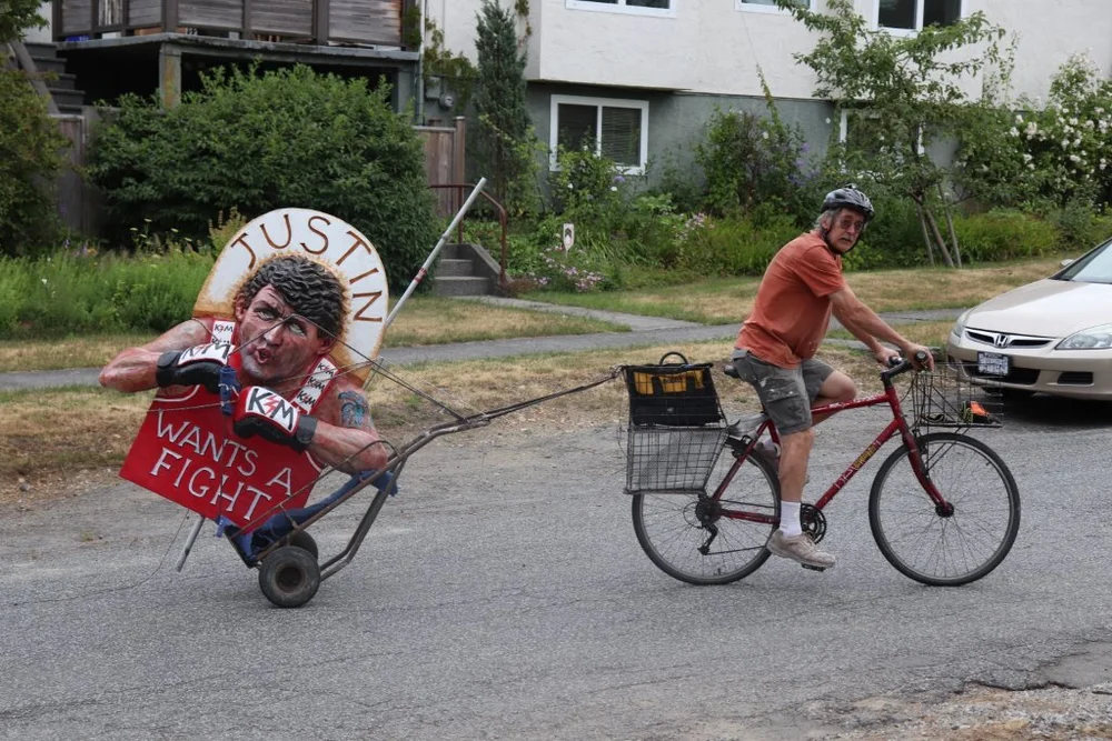 Figure 1: George Rammell on the way to his studio, with protest puppet, Justin Wants a Fight (2018), July 2018.