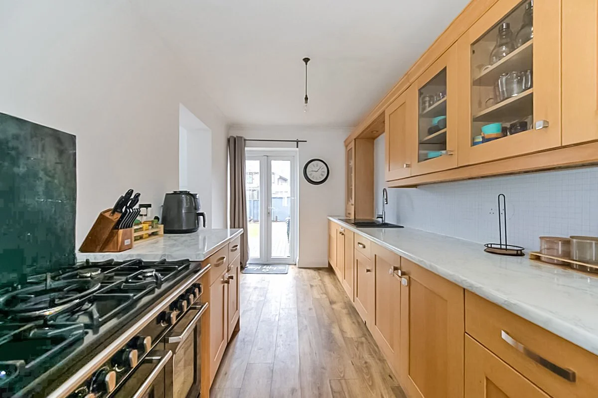 Kitchen with wooden cabinets, white countertops, gas stove, appliances, and glass door leading outside.