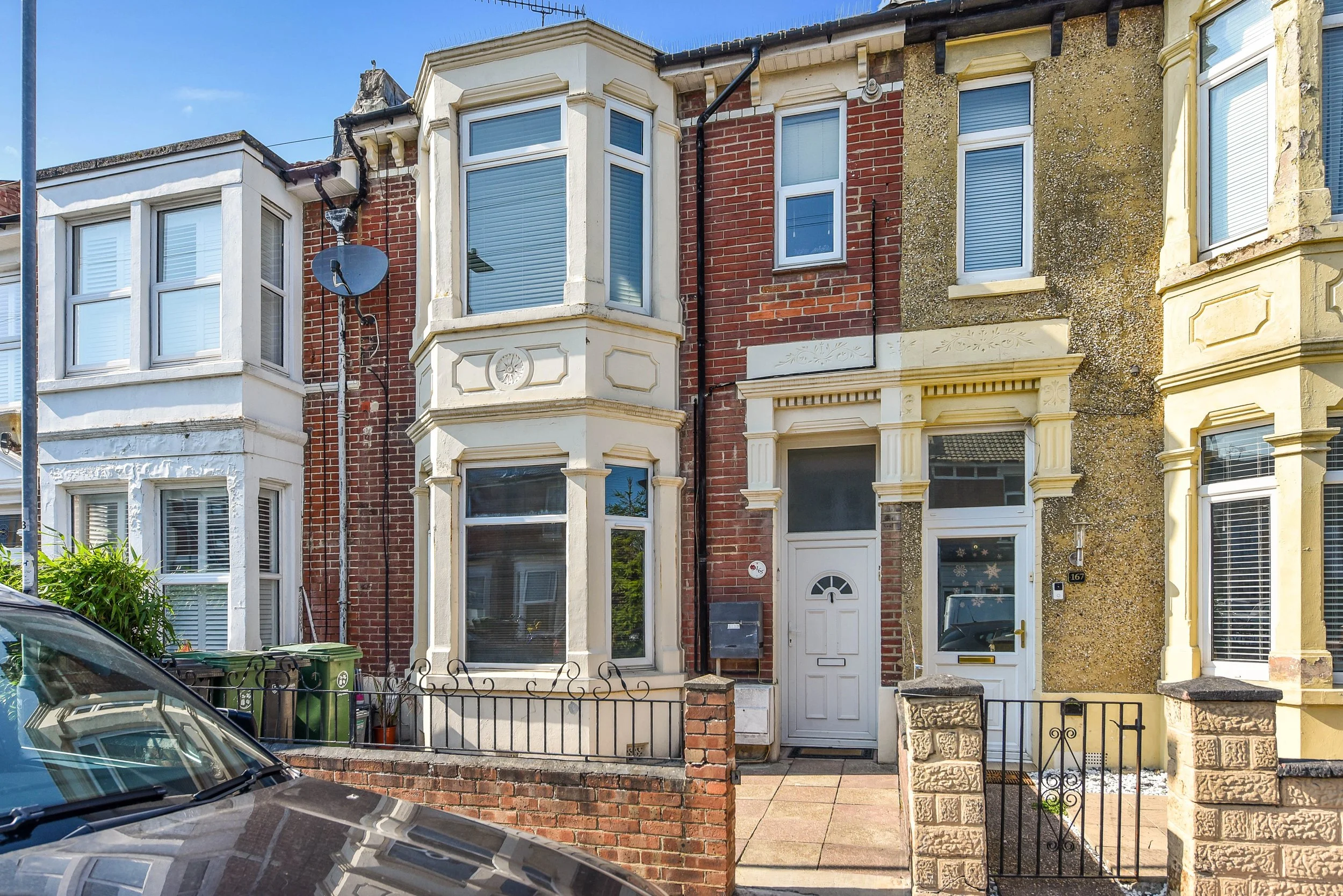 Row of Victorian-style terraced houses with bay windows, brick and stucco facades, in a residential neighborhood.