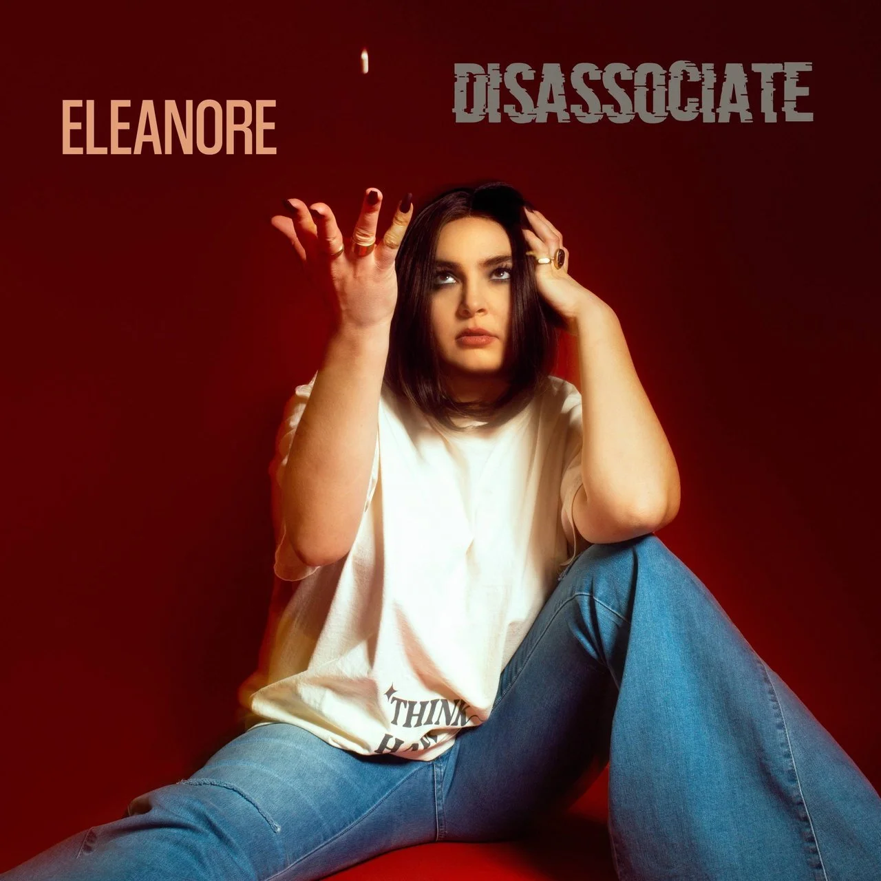 A woman with dark hair, wearing a white t-shirt and blue jeans, sitting against a red background, with an intense expression and reaching hand gesture, featuring text overlays with her name Eleanor, the word Disassociate, and a partially visible quot