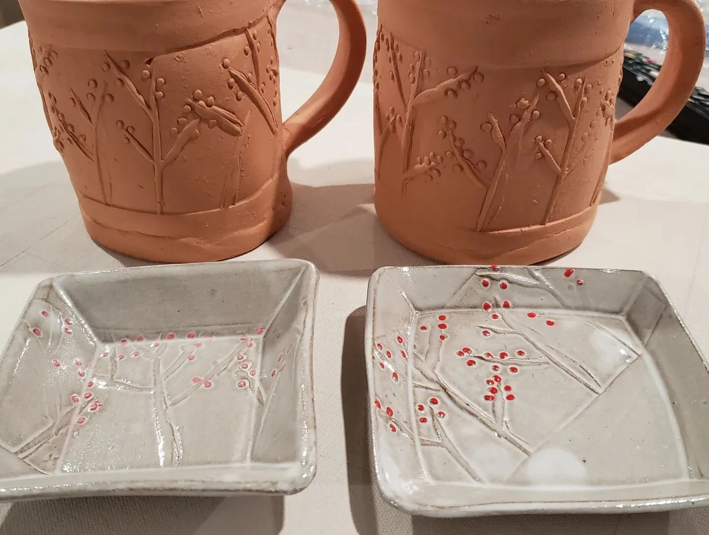 Which one? The two little dishes are tests for these mugs. The one on the left has the little red dots underneath the cream glaze and the one on the right has the red dots on top. I'm leaning towards the one on the right. Or do you think it should be