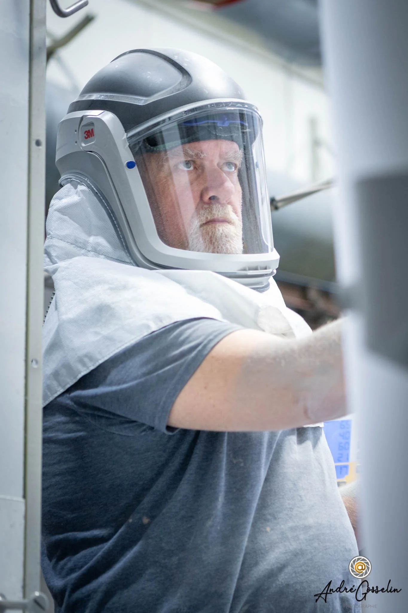 Portrait industriel - Un homme portant un casque intégral de protection se prépare dans un environnement clinical ou industriel.