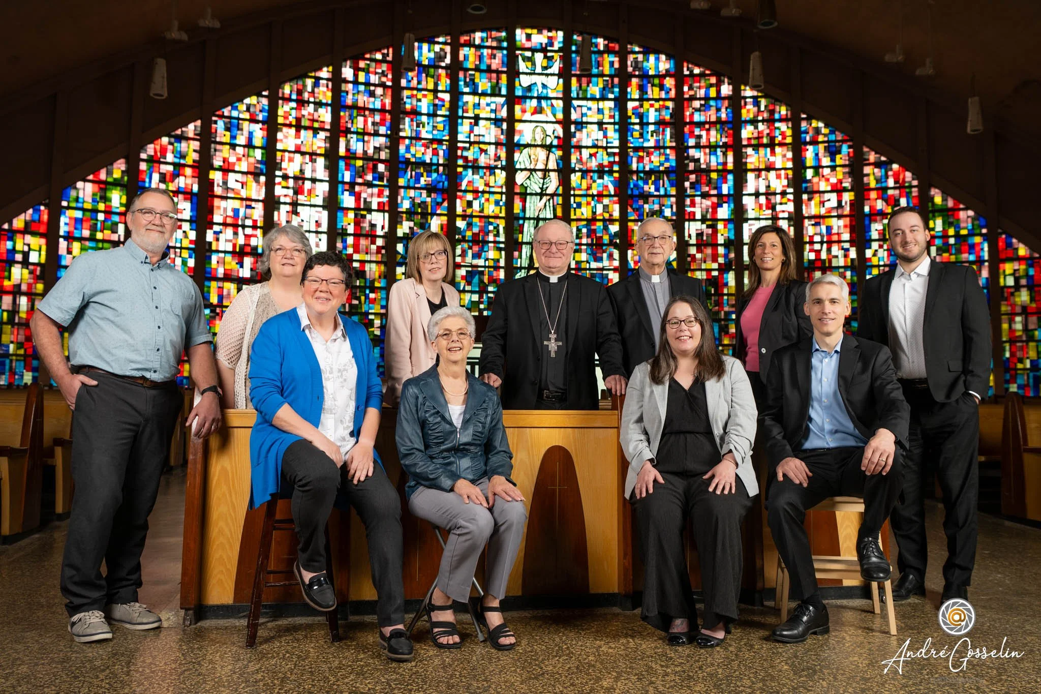 Groupe de personnes posant à l'intérieur d'une église avec un vitrail coloré en arrière-plan. Photo de groupe corporative.