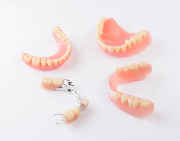 A set of dental prosthetics including dentures, partial denture, and individual false teeth on a white background.