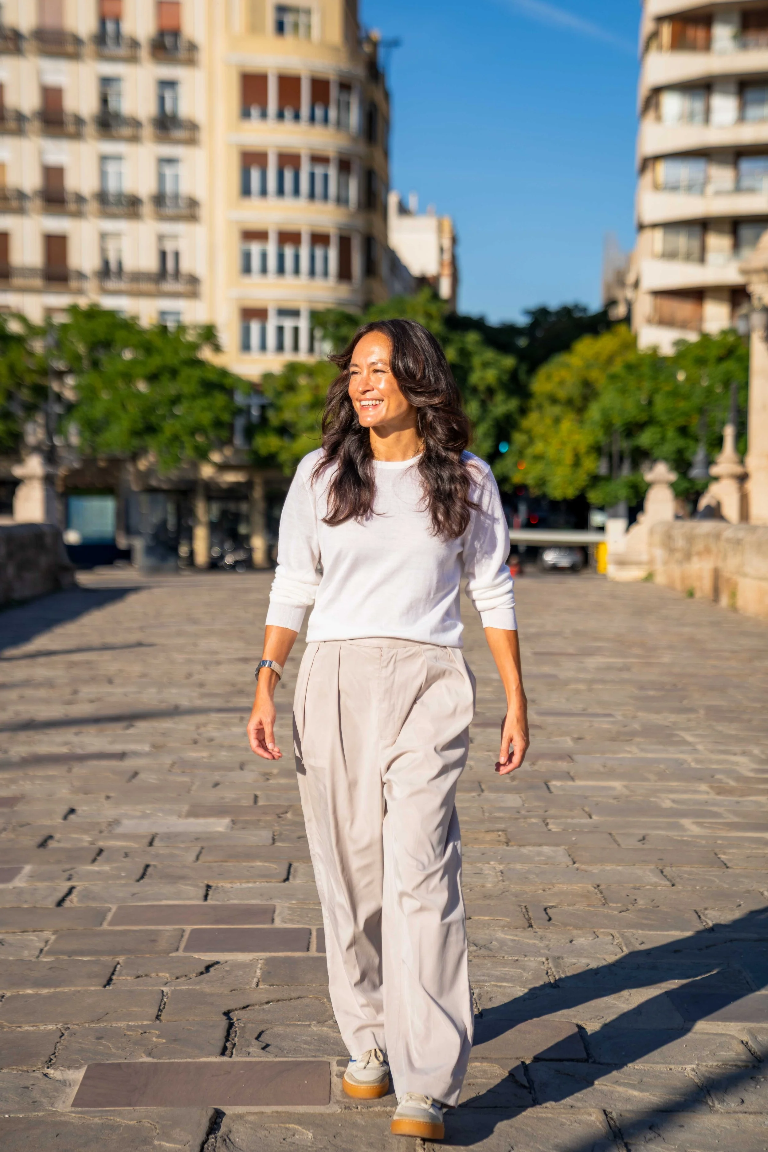 Stephanie Kirtley, co-founder of Encantada World, walking across a historic stone bridge in Valencia