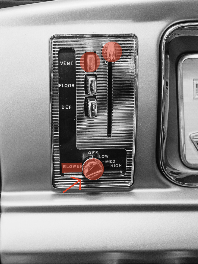 Dashboard control panel with a graduated slide thermometer, toggle switches, and a red knob labeled "BLOWER" with an arrow pointing to it.