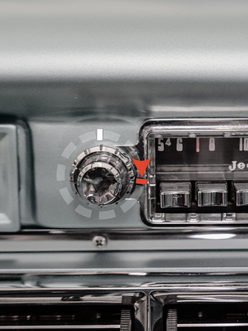Close-up of a vintage car radio and control knob, with a red arrow pointing to the knob.