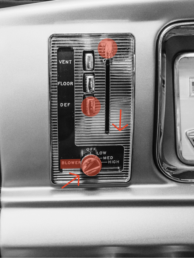 A vintage car dashboard with a vertical row of controls, including a vent, floor, and defrost options, a slider with an arrow pointing downward, a red button labeled 'BLOWER,' and a round knob with settings for off, low, medium, and high.