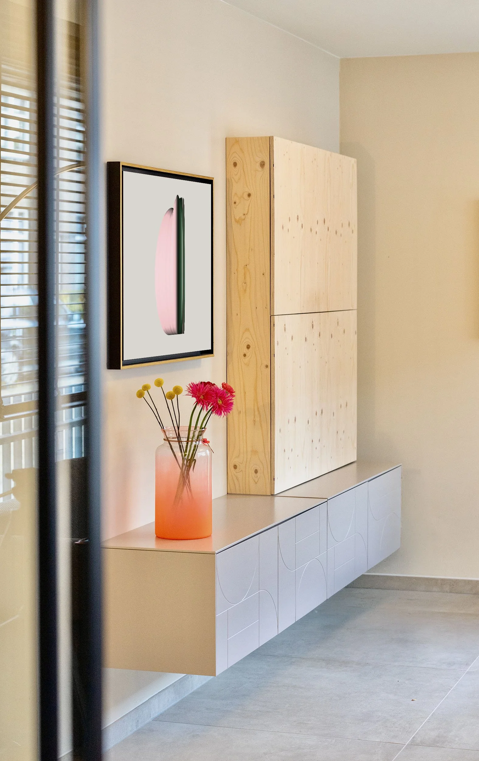 CharlotteMixt-interieurontwerp-Zijdelings doorkijkje naar zwevend dressoir met grijze deuren, multiplex kast, kunstwerk 'Clouds#1' pop-art en oranje vaas met bloemen. Jaloezieën deels zichtbaar op voorgrond.