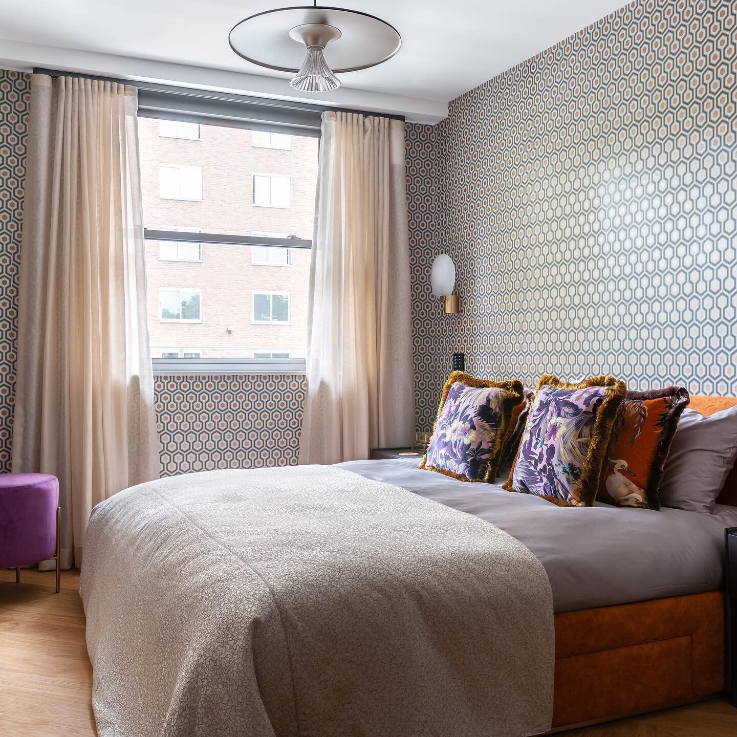 Recently completed site by @interworldfurnishings - This bedroom designed by @kirangala_and_associates spells luxury all over with its orange bed &amp; purple poof set against the backdrop of the geometric patterned wallpaper. 
Photo @uliana.grishina