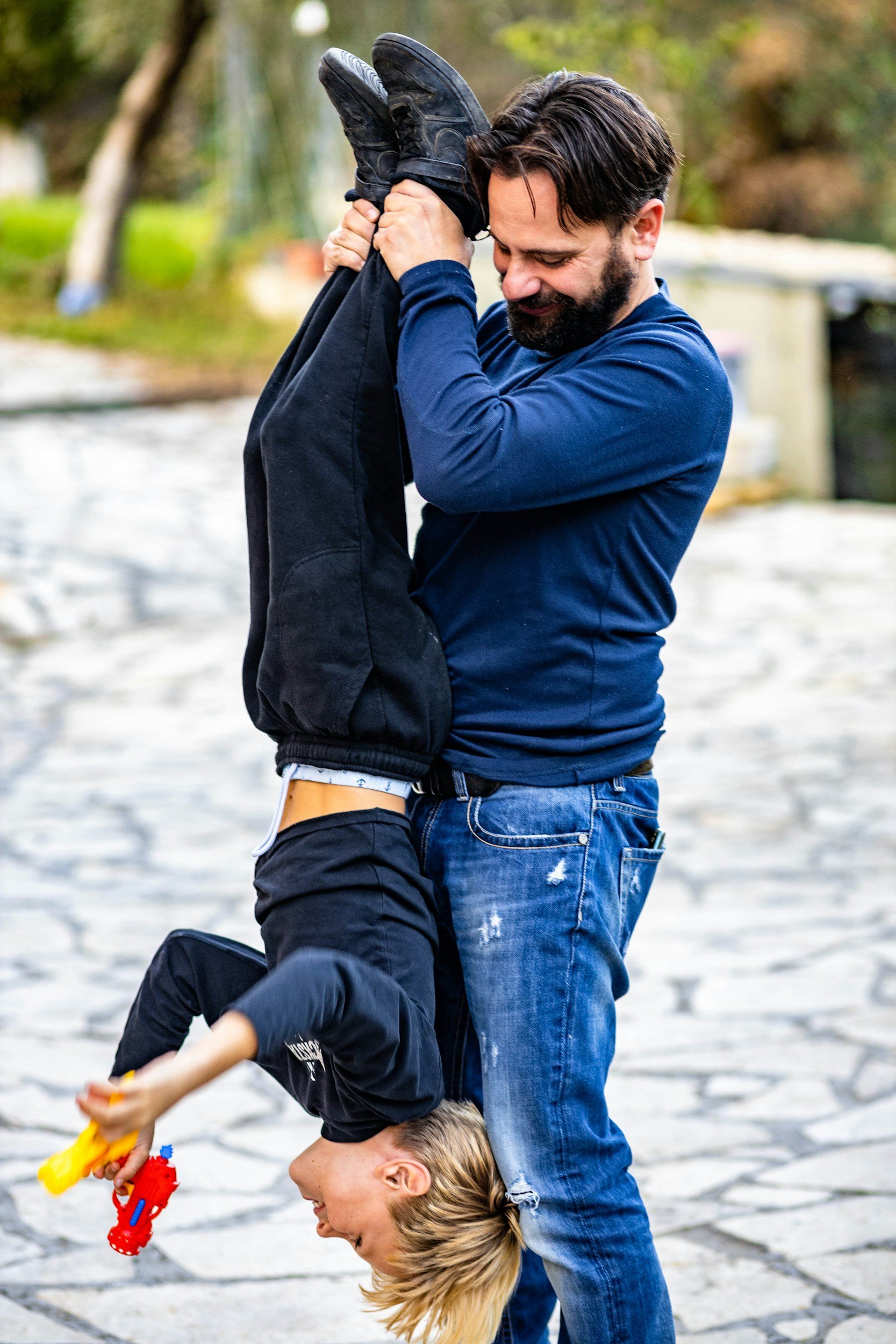 rough and tumble play with dad holding smiling kid upside down