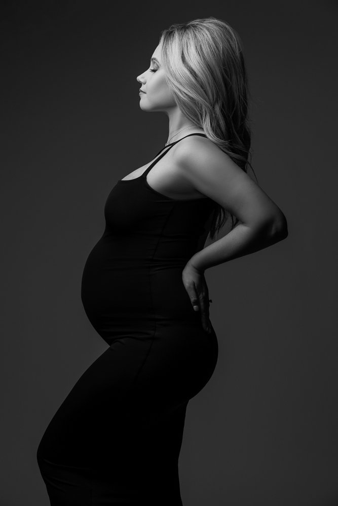 expectant-mother-in-black-gown-cradling-her-baby-bump.jpg