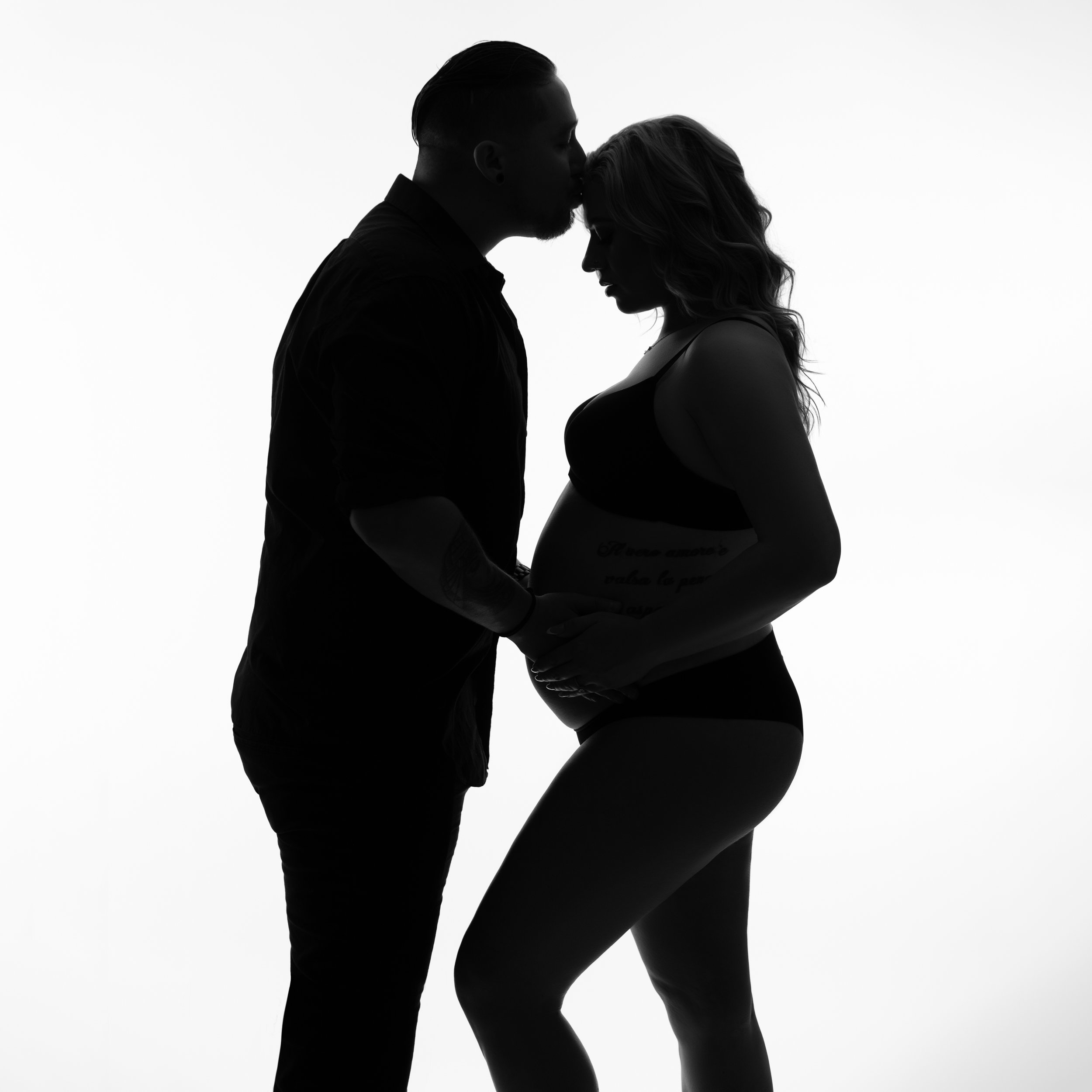 wife-and-husband-embracing-baby-bump-together-in-black-and-white-silhouette.jpg