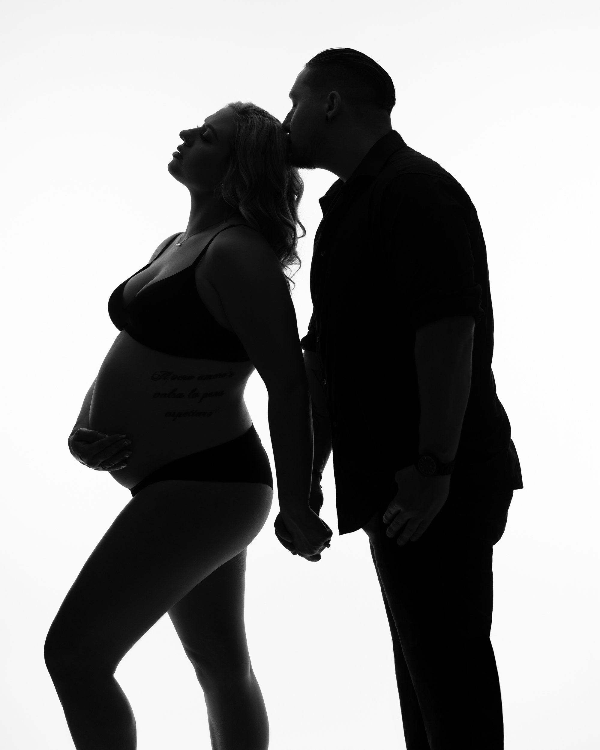 wife-and-husband-embracing-baby-bump-together-in-black-and-white-silhouette-with-kiss.jpg