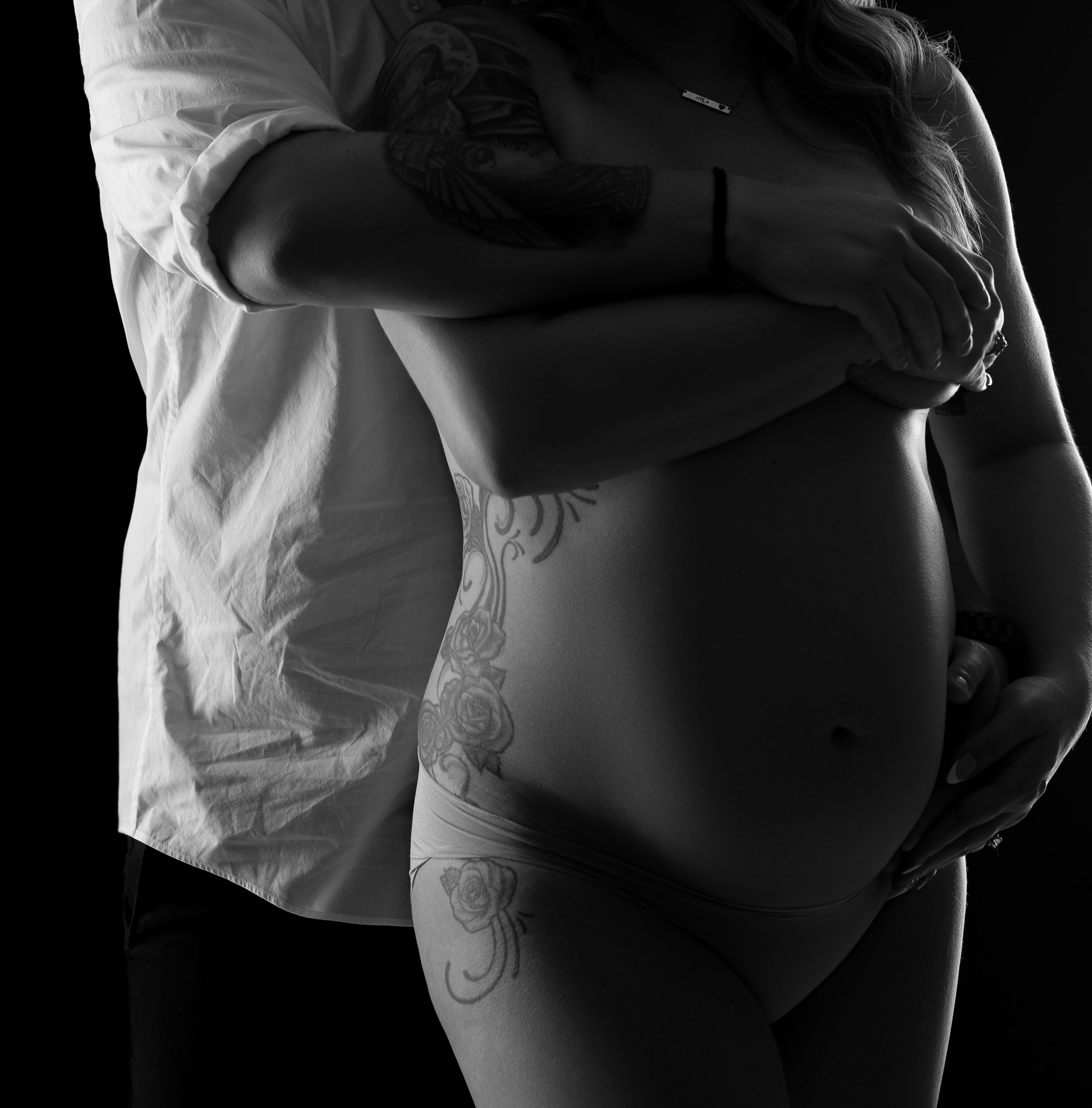 wife-and-husband-embracing-baby-bump-together-in-black-and-white-bodyscape.jpg