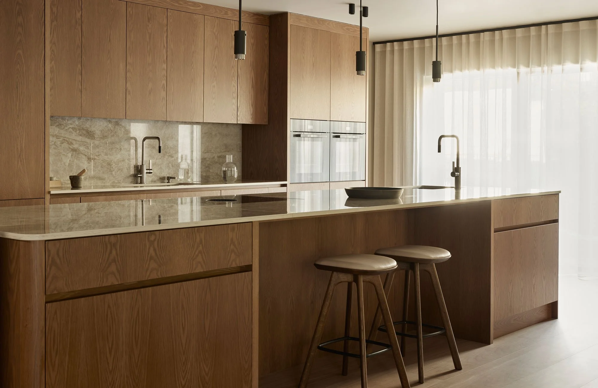 Kjøkkenøy i varm eik med innebygde skuffer og benkeplate i lys komposittstein